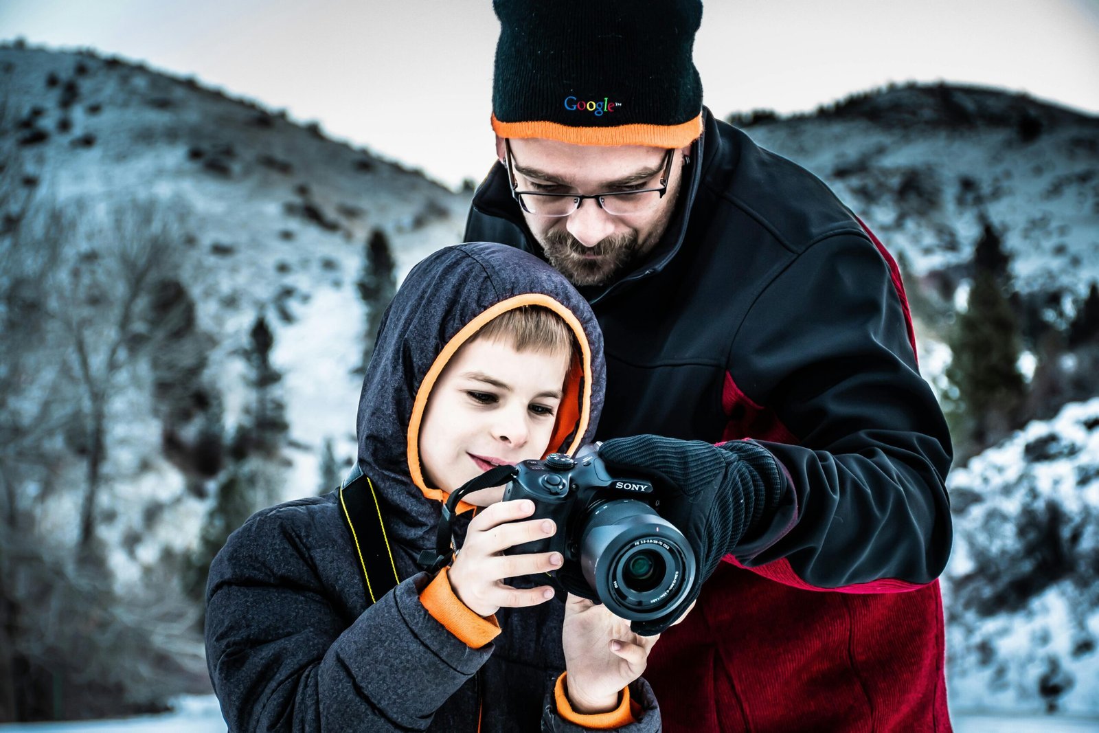 Father teaching his son outdoor photography on a winter day. Bonding over capturing snowy landscapes.